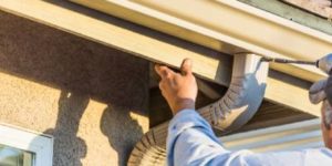 Signs You Need Gutter Replacement Man outside home replacing gutters